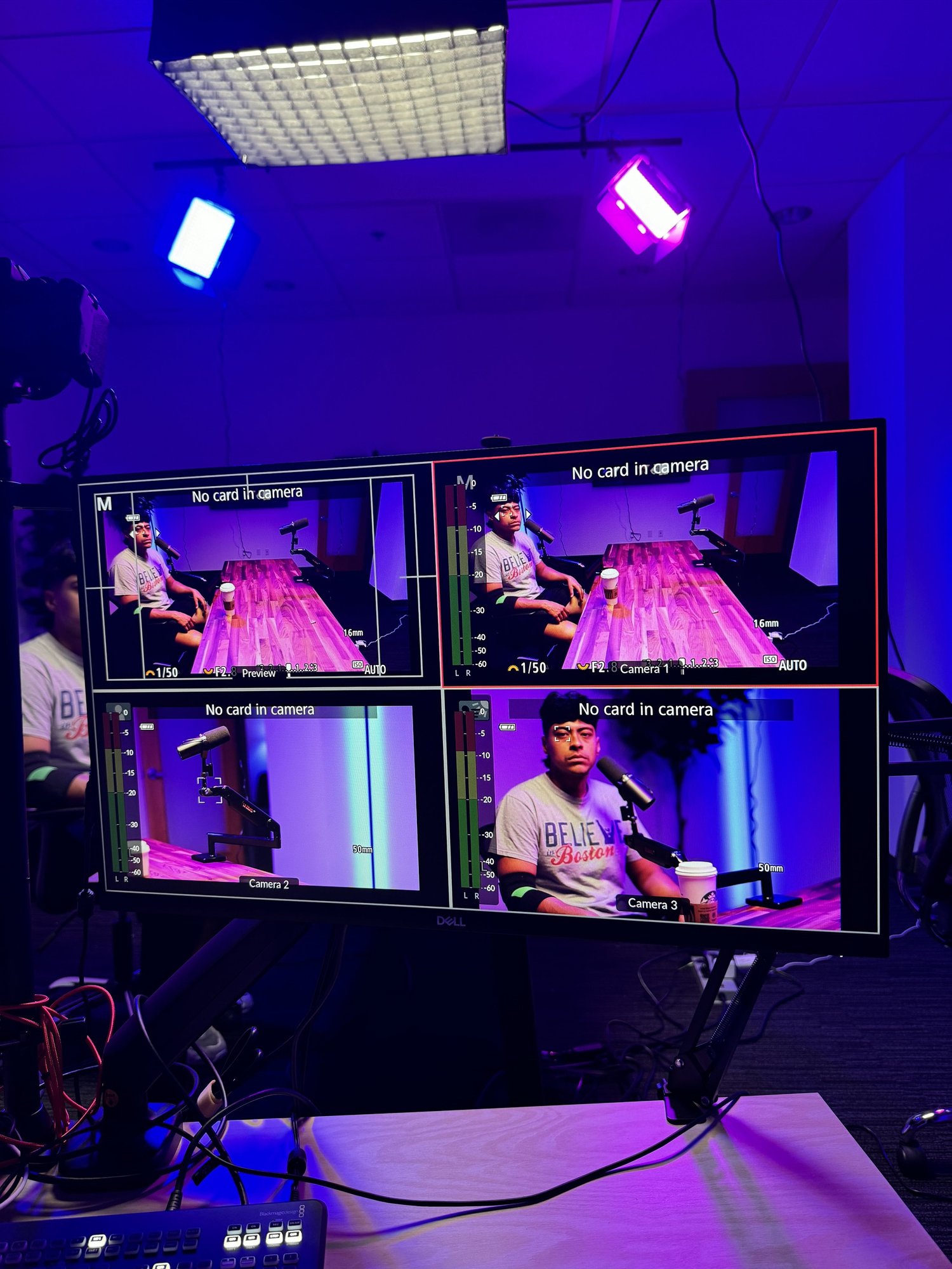 TV monitor displaying four camera feeds of a person at a microphone