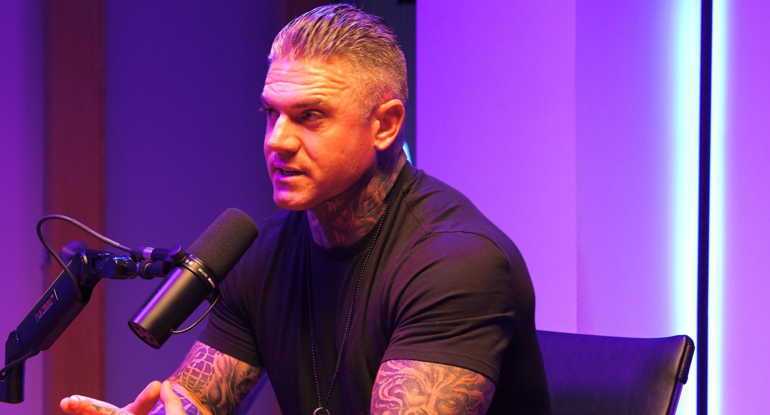 Man speaking into a microphone with purple and blue lighting